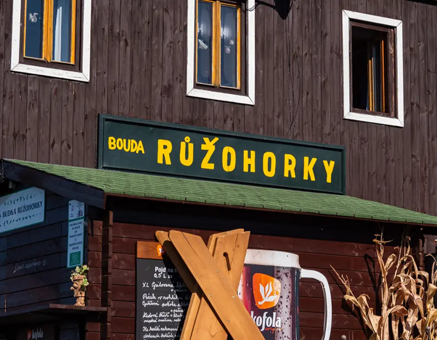 Drewniana górska chata Bouda Růžohorky z zielonym szyldem na szlaku na Śnieżkę w czeskich Karkonoszach